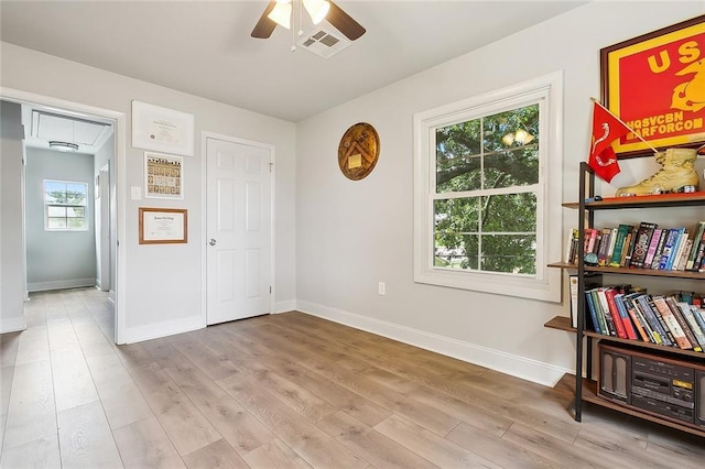 interior space with light wood-type flooring, attic access, visible vents, and ceiling fan