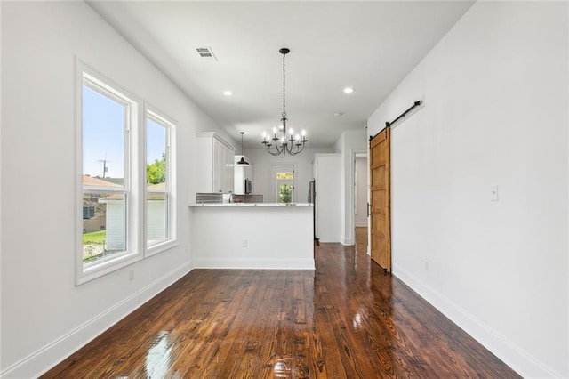 interior space with kitchen peninsula, dark wood-type flooring, white cabinetry, and a barn door