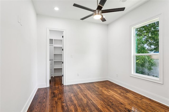 unfurnished bedroom featuring ceiling fan, a closet, a spacious closet, and wood-type flooring