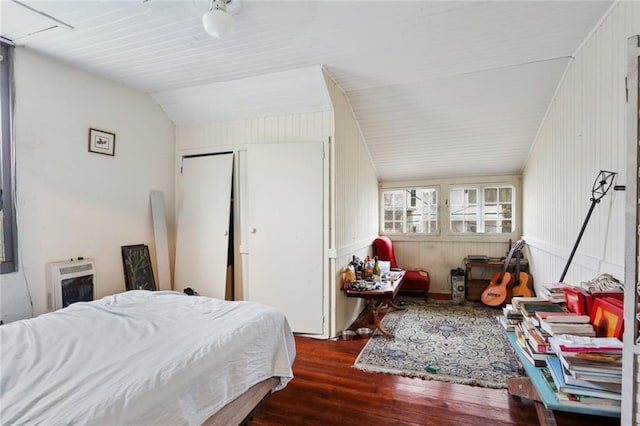 bedroom with heating unit, lofted ceiling, and hardwood / wood-style floors