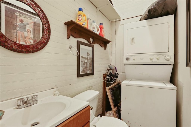 interior space with vanity, stacked washer / dryer, and toilet