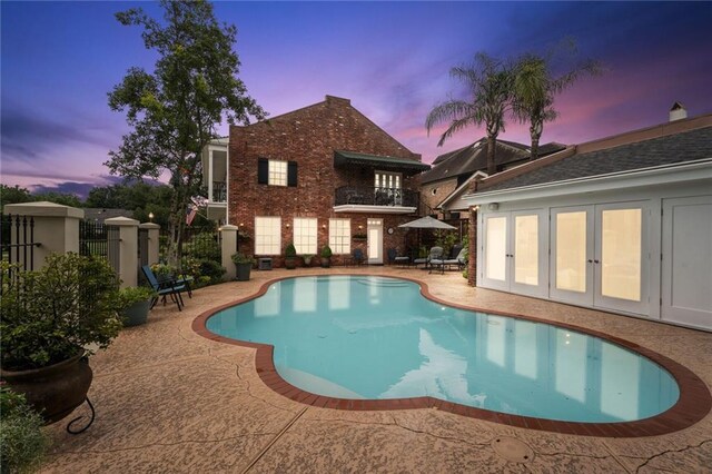 pool at dusk with a patio area