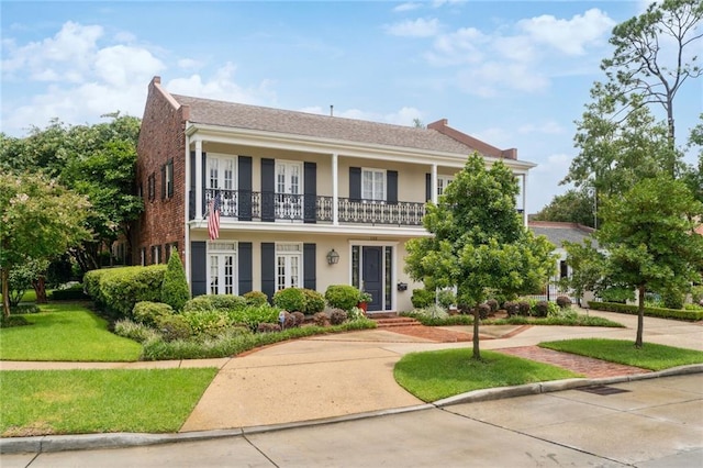 view of front of home featuring brick siding, stucco siding, a chimney, french doors, and a front yard