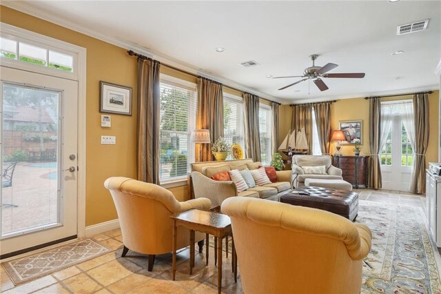 tiled living room with ceiling fan, a wealth of natural light, and ornamental molding