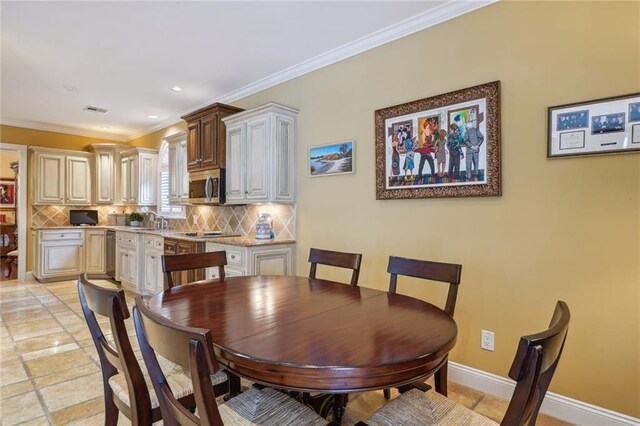 dining area with sink, crown molding, and light tile patterned flooring