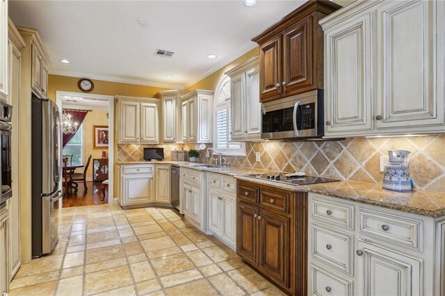 kitchen featuring a wealth of natural light, light stone countertops, black appliances, and backsplash