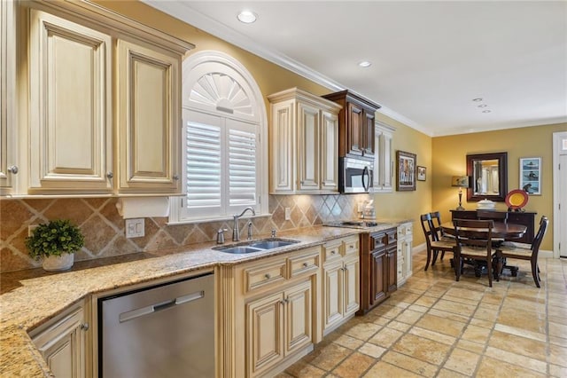 kitchen with baseboards, appliances with stainless steel finishes, light stone counters, ornamental molding, and a sink