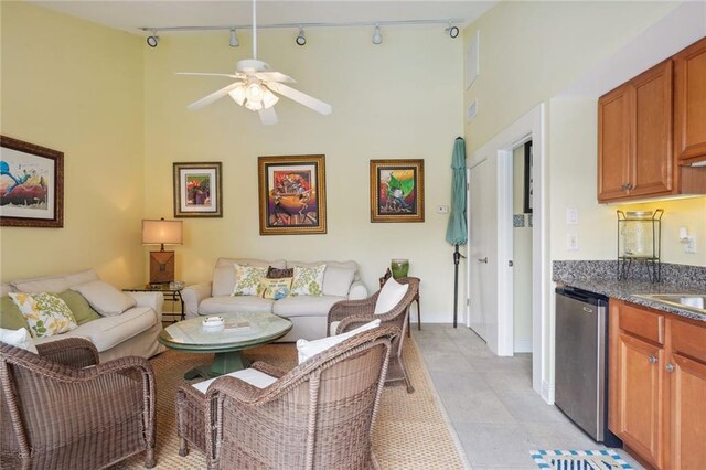 living room with ceiling fan, track lighting, a high ceiling, and light tile patterned floors