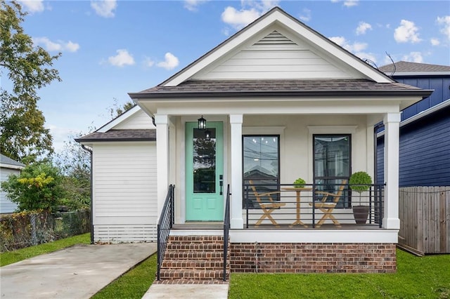 view of front of house featuring a porch, roof with shingles, and fence