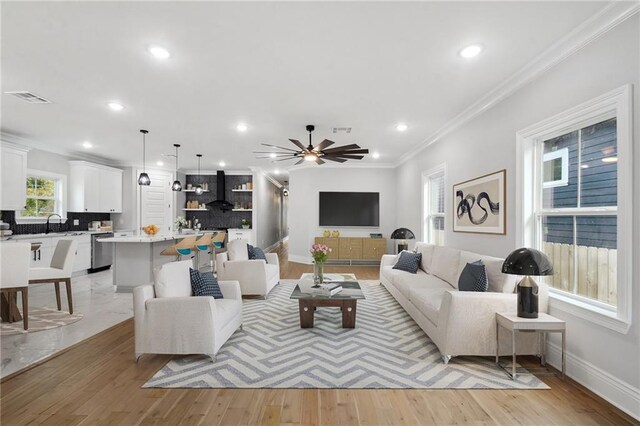 living room with light hardwood / wood-style floors, sink, crown molding, and ceiling fan