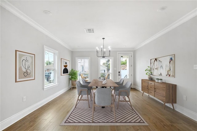 dining space featuring hardwood / wood-style flooring, an inviting chandelier, and ornamental molding