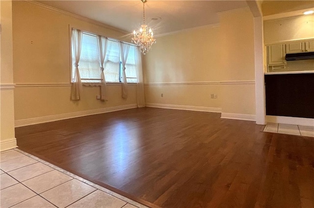 empty room featuring ornamental molding, an inviting chandelier, and light wood-type flooring