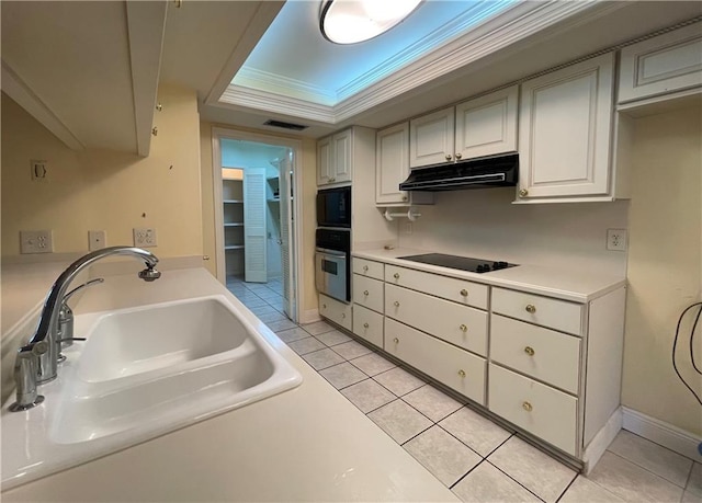 kitchen featuring sink, a tray ceiling, light tile patterned floors, black appliances, and white cabinets