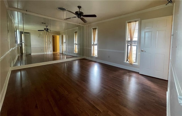 empty room with ceiling fan, a wealth of natural light, crown molding, and dark hardwood / wood-style flooring