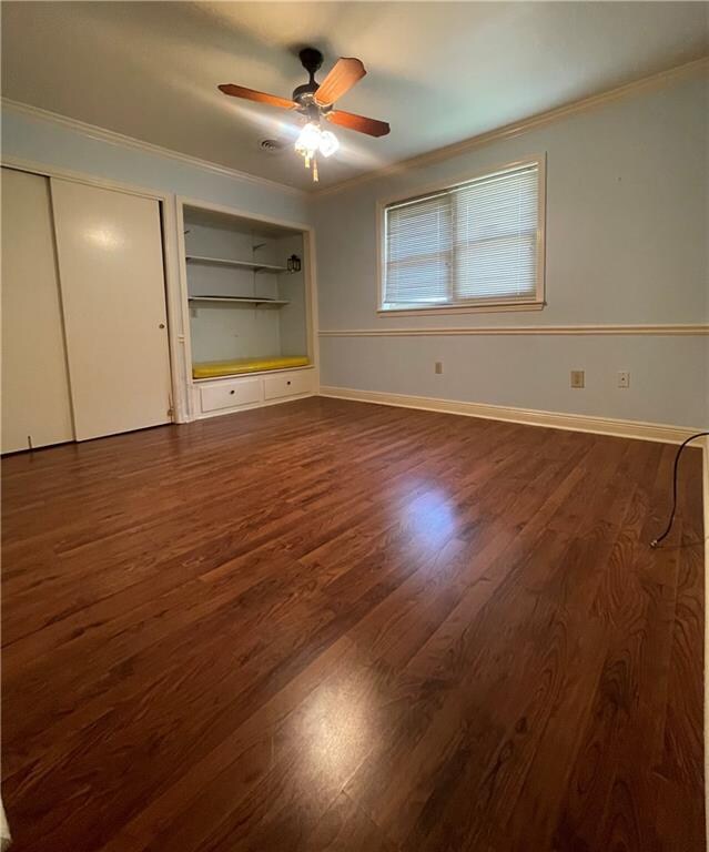 unfurnished bedroom featuring hardwood / wood-style floors, ornamental molding, and ceiling fan