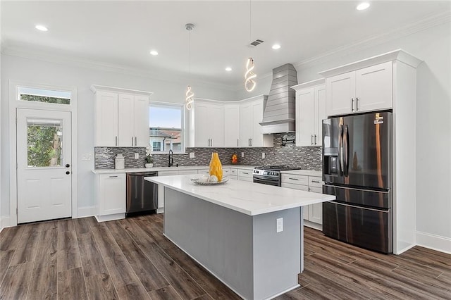 kitchen featuring backsplash, stainless steel appliances, a kitchen island, and premium range hood