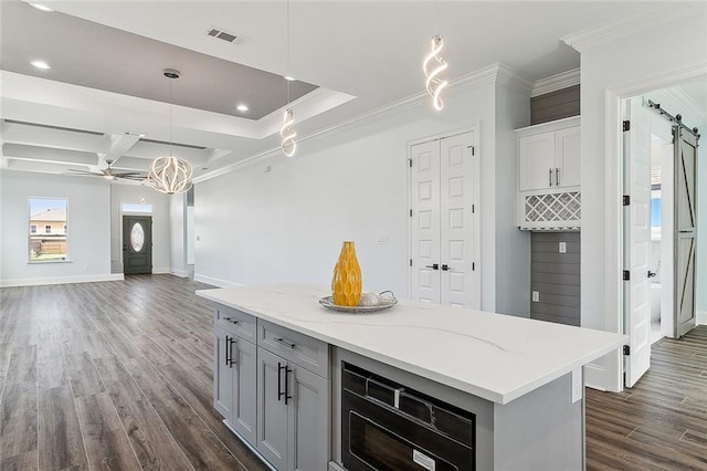 kitchen with dark hardwood / wood-style floors, coffered ceiling, a barn door, a kitchen island, and hanging light fixtures