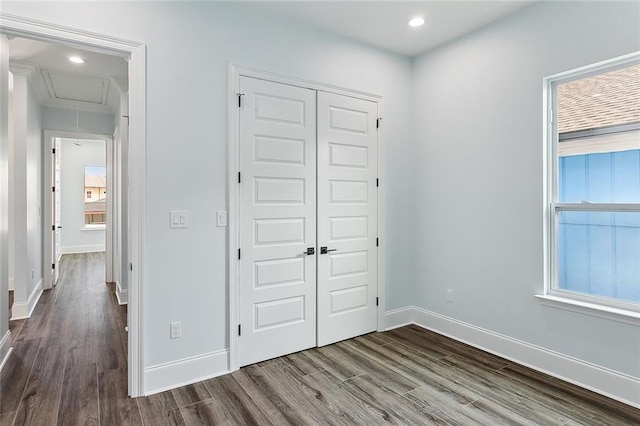 unfurnished bedroom with a closet, hardwood / wood-style floors, and multiple windows