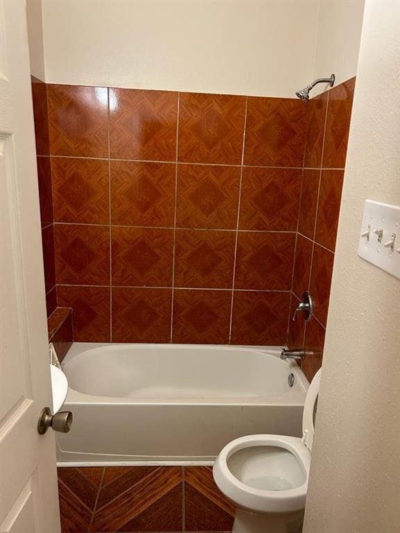 bathroom featuring tiled shower / bath combo and toilet