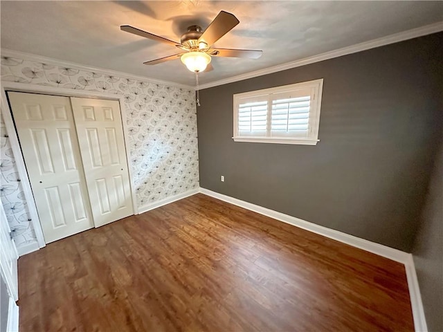 unfurnished bedroom featuring ceiling fan, ornamental molding, a closet, and wood-type flooring