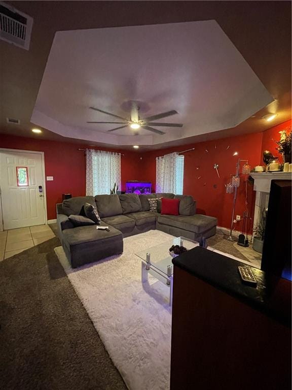 living room with ceiling fan, a raised ceiling, and carpet