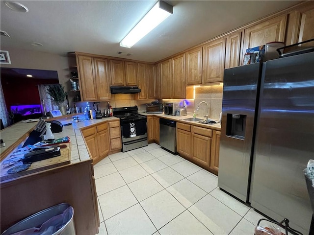 kitchen featuring light tile patterned flooring, sink, kitchen peninsula, stainless steel appliances, and backsplash