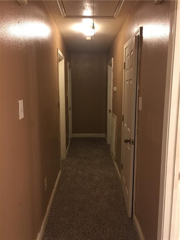 hall featuring dark colored carpet