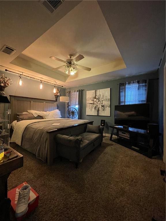 carpeted bedroom with a tray ceiling and ceiling fan