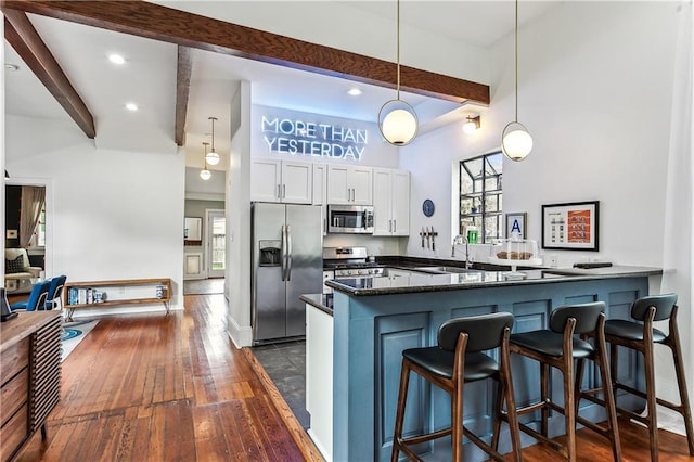 kitchen featuring white cabinetry, beamed ceiling, kitchen peninsula, pendant lighting, and appliances with stainless steel finishes