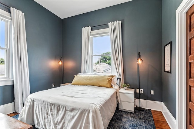 bedroom with dark wood-type flooring and multiple windows