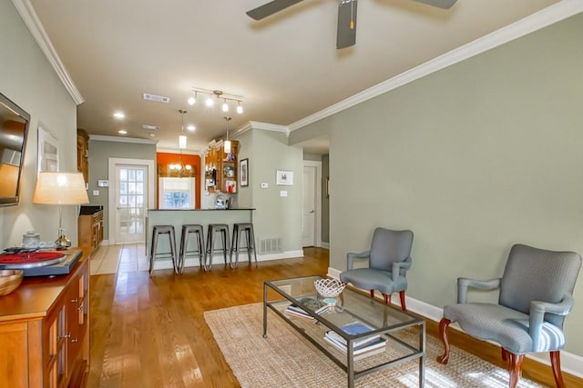 living room featuring ceiling fan, ornamental molding, light wood-type flooring, and track lighting