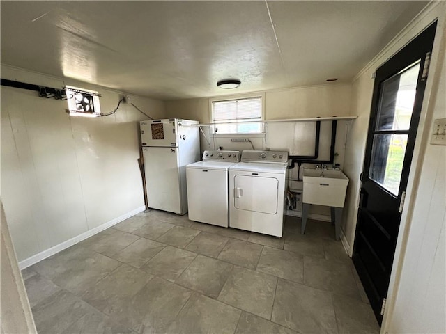 laundry room featuring sink, ornamental molding, light tile patterned floors, and washing machine and clothes dryer