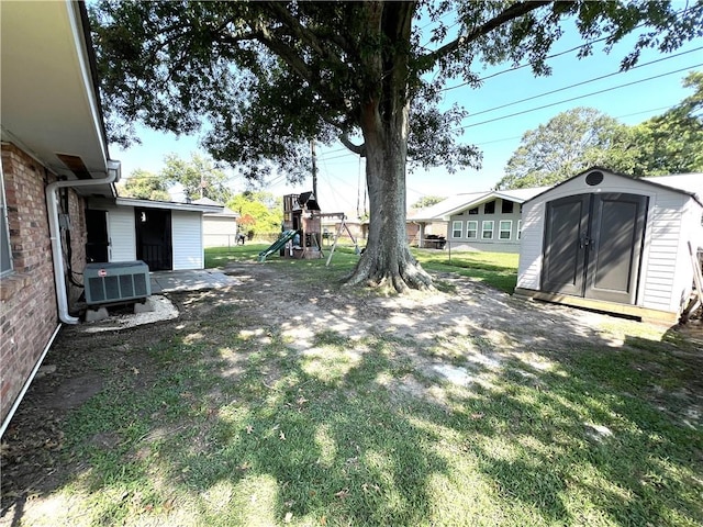 view of yard featuring central air condition unit, a shed, and a playground