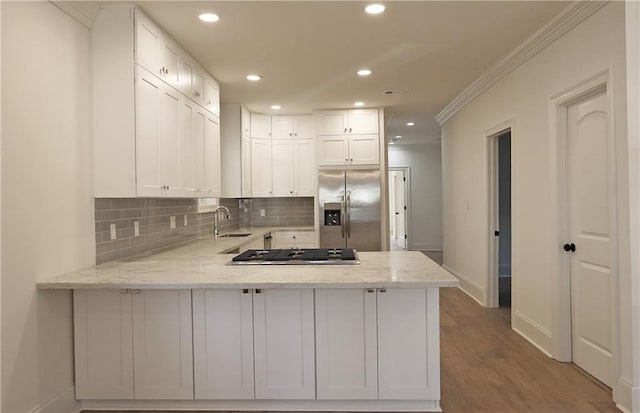 kitchen featuring stainless steel appliances, light hardwood / wood-style floors, sink, crown molding, and kitchen peninsula