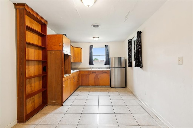 kitchen with light countertops, freestanding refrigerator, visible vents, and light tile patterned floors