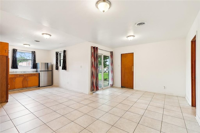 empty room with visible vents, a sink, and light tile patterned floors