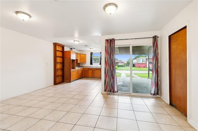 unfurnished living room with light tile patterned flooring and baseboards