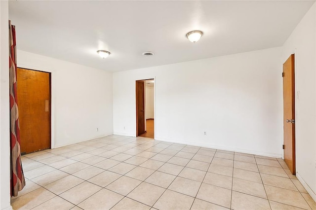 unfurnished room with light tile patterned floors, visible vents, and baseboards