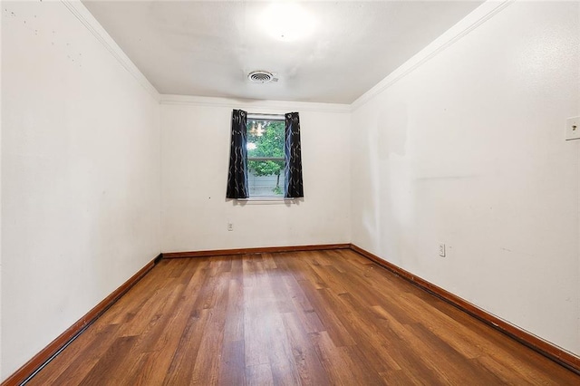 unfurnished room featuring baseboards, visible vents, wood finished floors, and ornamental molding