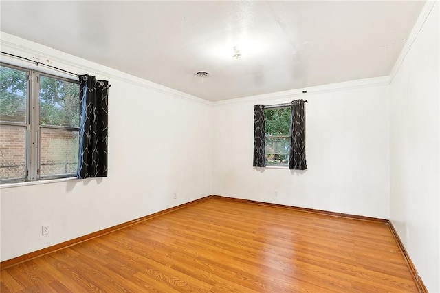 spare room with ornamental molding, wood finished floors, visible vents, and baseboards