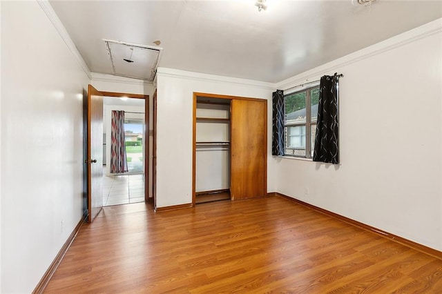 unfurnished bedroom featuring light wood-type flooring, multiple windows, and crown molding