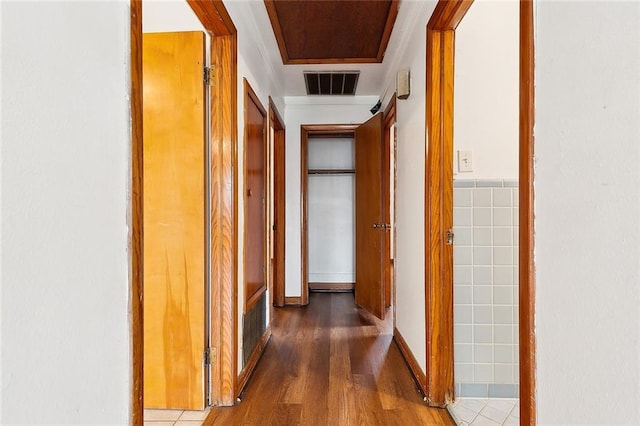 hall with tile walls, visible vents, and wood finished floors