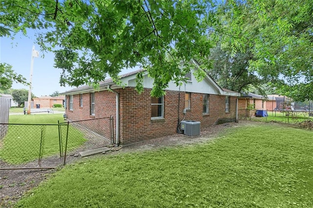 view of property exterior with central AC, brick siding, fence, and a lawn