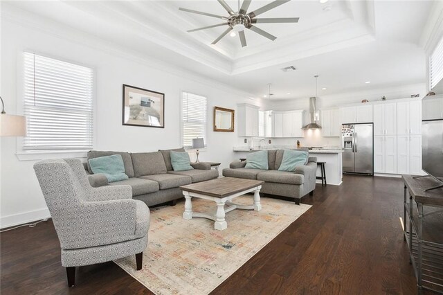 living room with sink, hardwood / wood-style flooring, a tray ceiling, ceiling fan, and crown molding