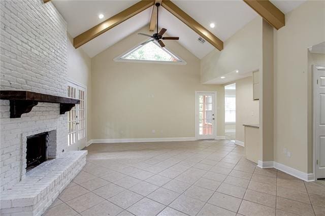 unfurnished living room featuring a wealth of natural light, ceiling fan, beamed ceiling, and a fireplace