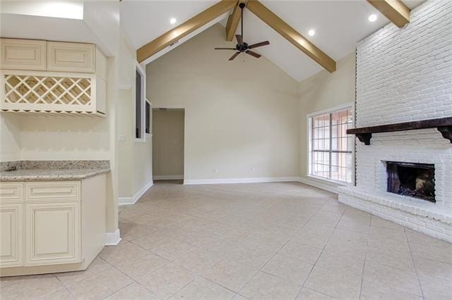 unfurnished living room with light tile patterned flooring, beam ceiling, a fireplace, high vaulted ceiling, and ceiling fan