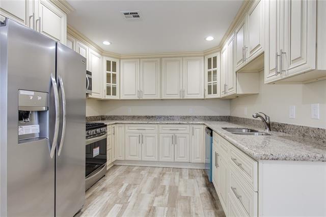 kitchen featuring light stone countertops, appliances with stainless steel finishes, light wood-type flooring, and sink