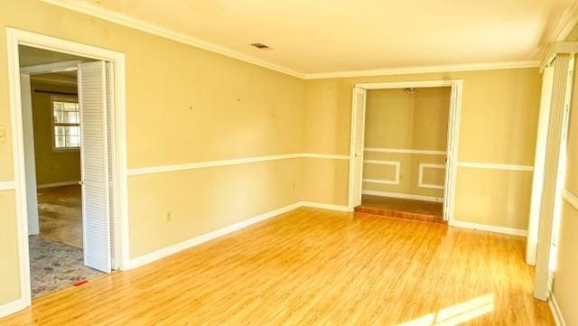 unfurnished room with ornamental molding, wood finished floors, and baseboards