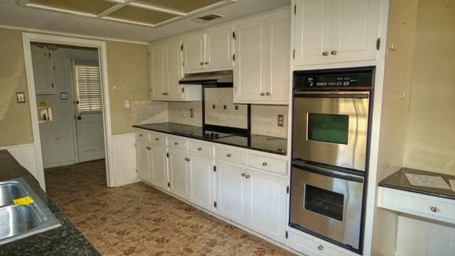 kitchen featuring double oven, dark countertops, white cabinetry, and under cabinet range hood