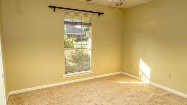 carpeted empty room with ceiling fan and baseboards